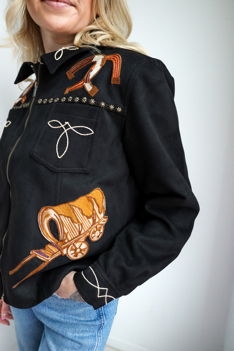 Black jacket with orange and white designs worn by a person on a plain background