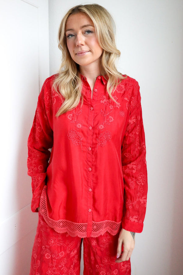 Person wearing red pajama set standing against a white wall