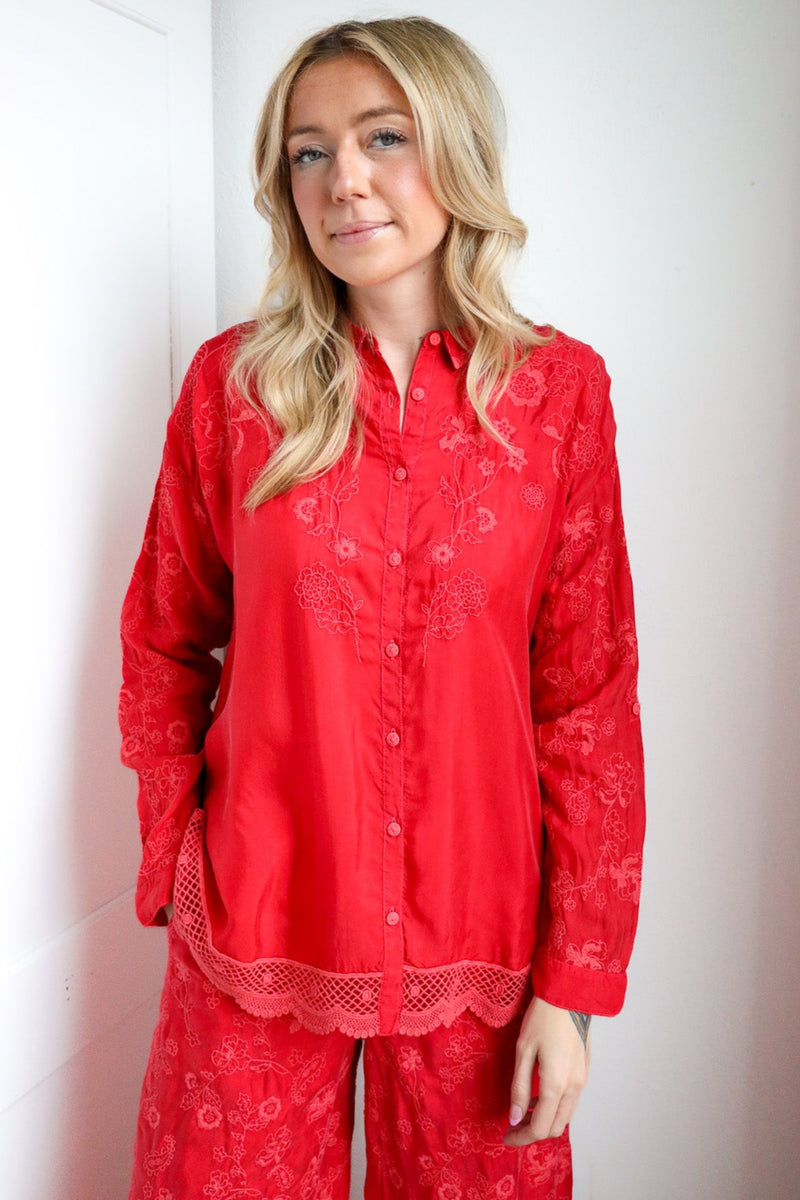 Person wearing red pajama set standing against a white wall