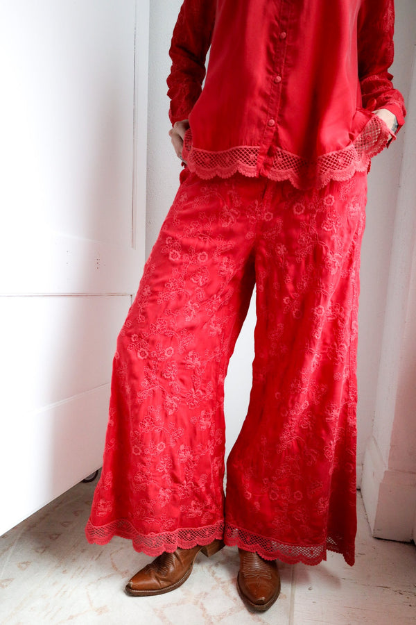 Person wearing a red lace outfit with wide-leg pants and a top.