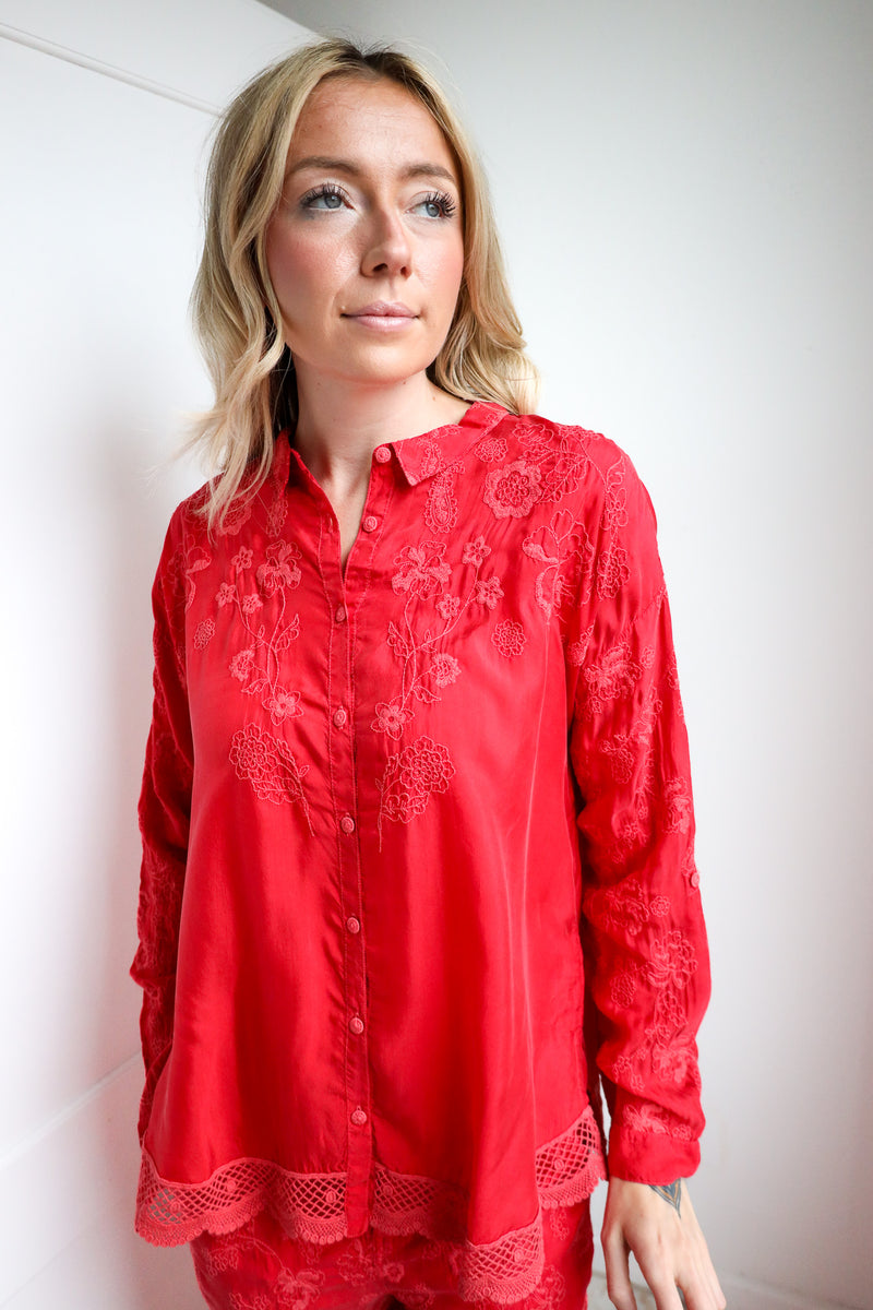 Woman wearing a red lace blouse against a white background