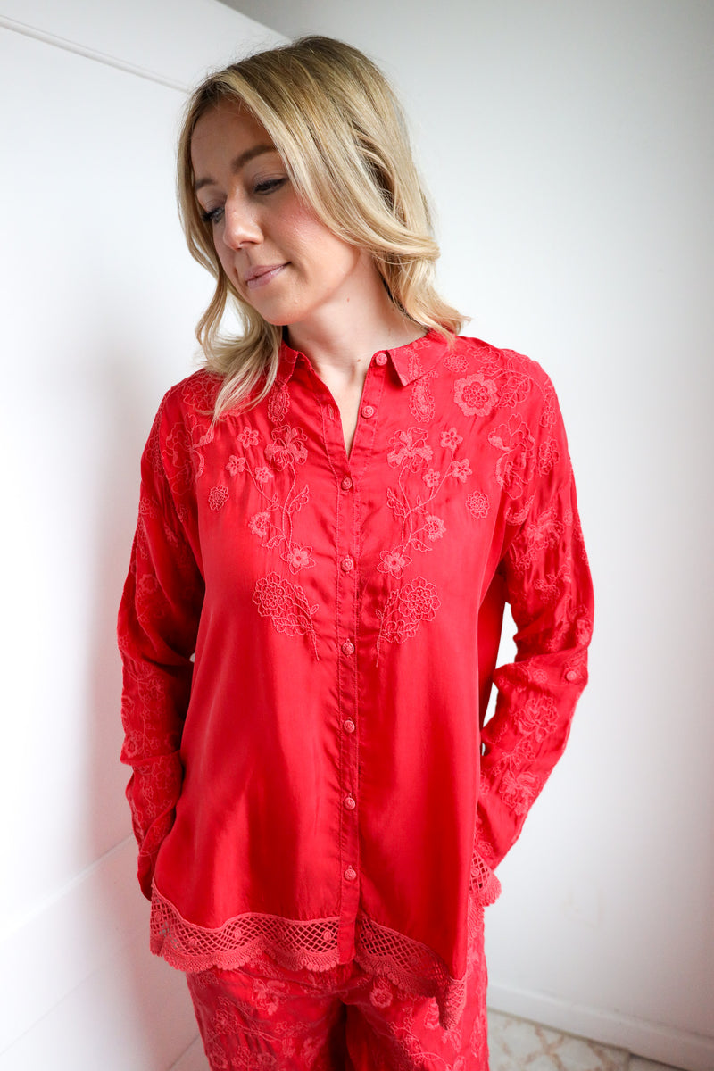 Woman wearing a red embroidered shirt and pants against a white background