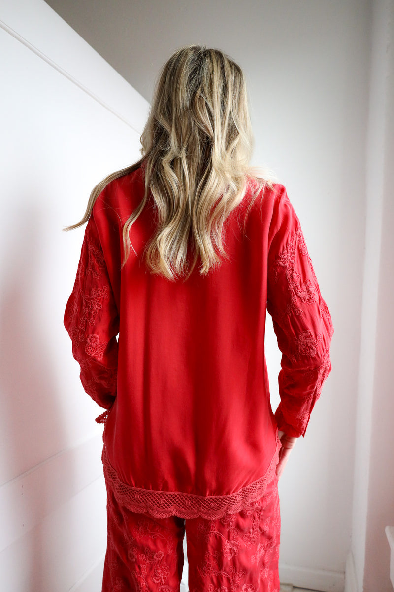 Person wearing a red outfit with lace details in a minimal indoor setting