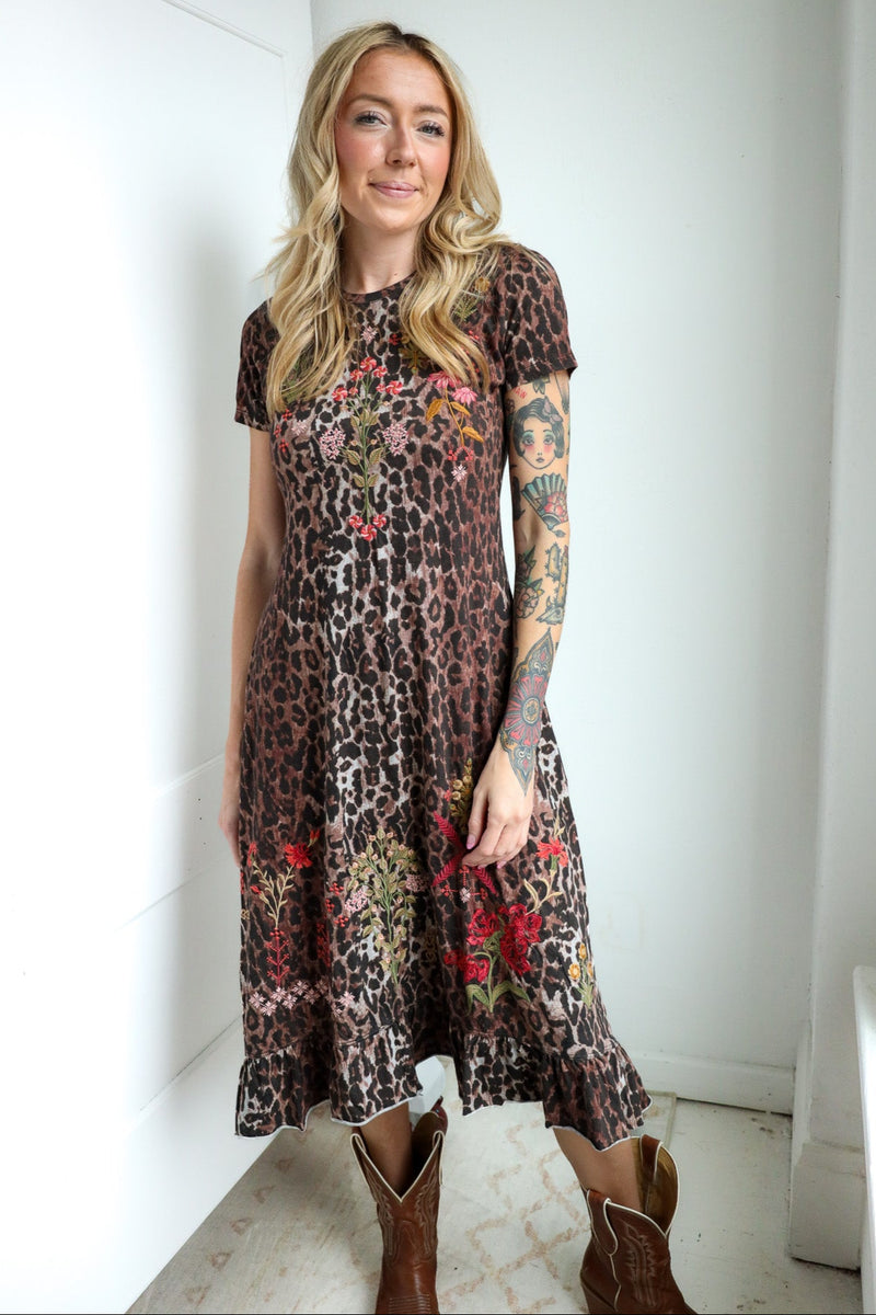 Woman wearing a floral and leopard print dress with brown boots indoors.