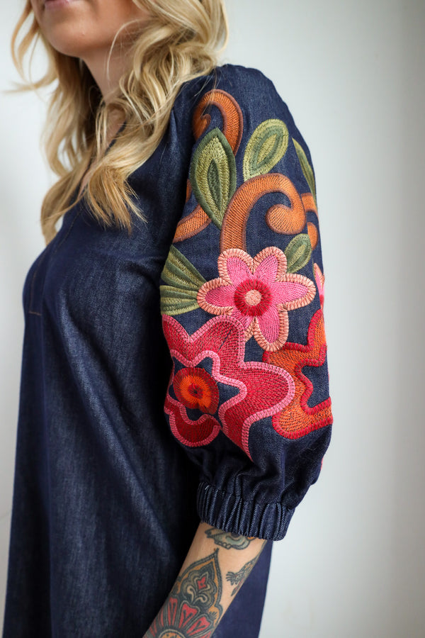 Navy blue garment with colorful floral embroidery on a plain background