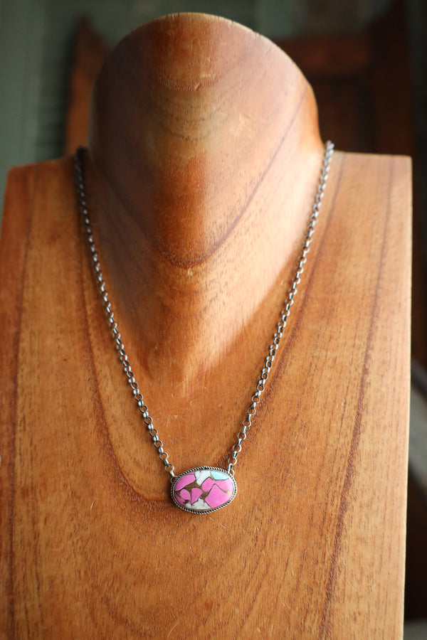 Necklace with a pink floral pendant on a wooden mannequin