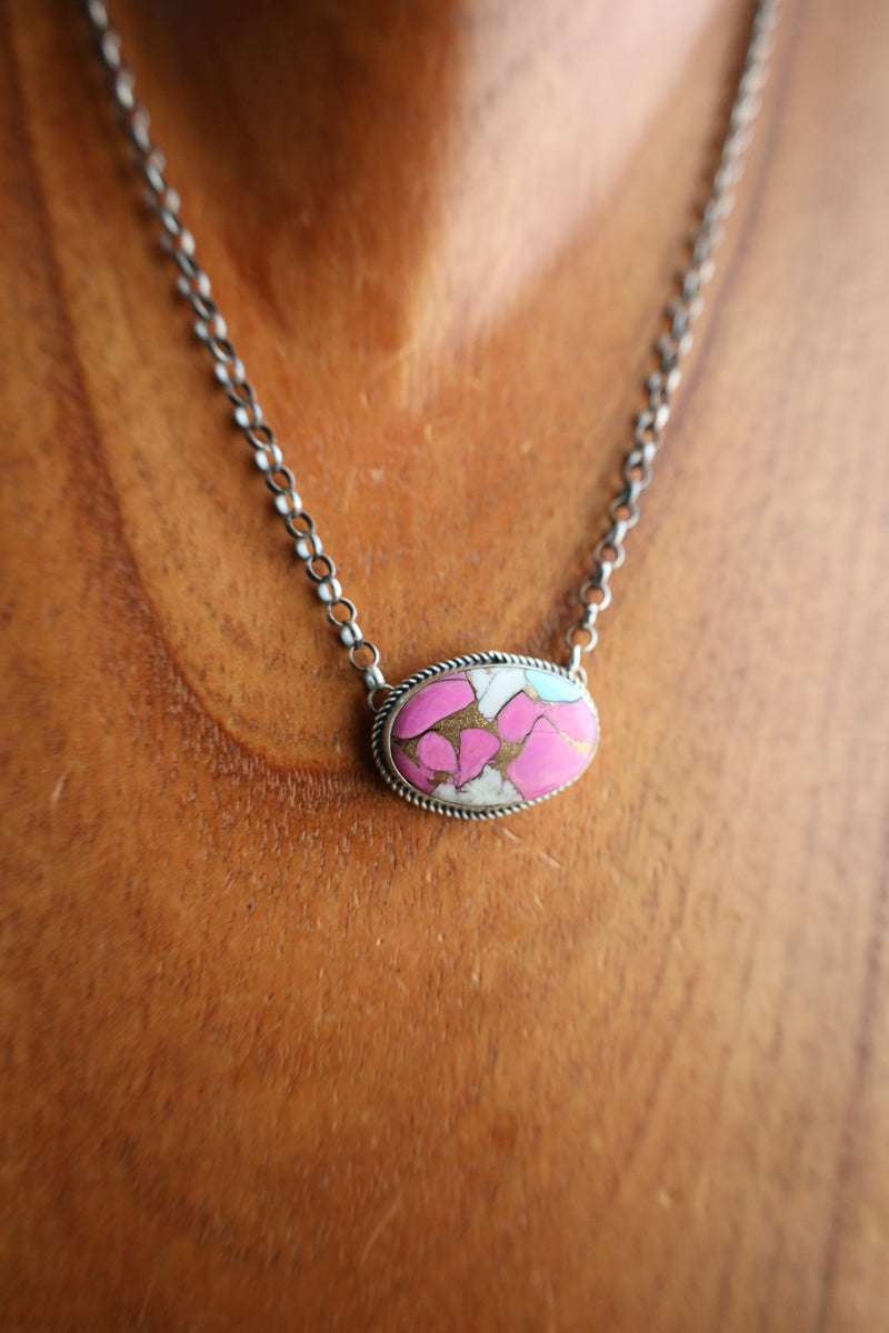 Necklace with a pink and white pendant on a wooden surface