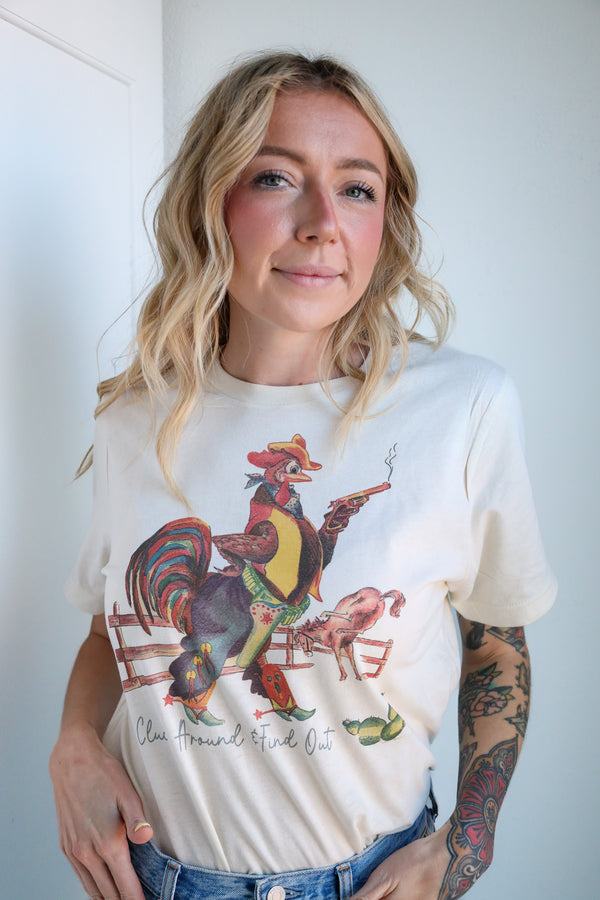 Person wearing a white t-shirt with a colorful rooster design against a plain background