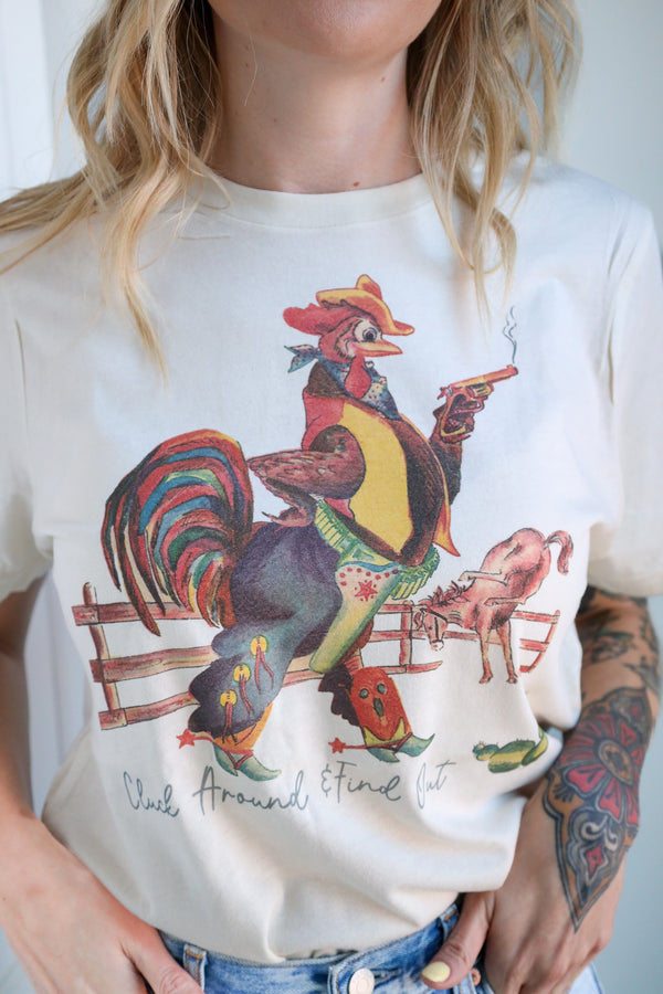 Person wearing a white t-shirt with a colorful graphic of a rooster and a pig, with text 'Chick Around a Fine Lot' on a plain background.