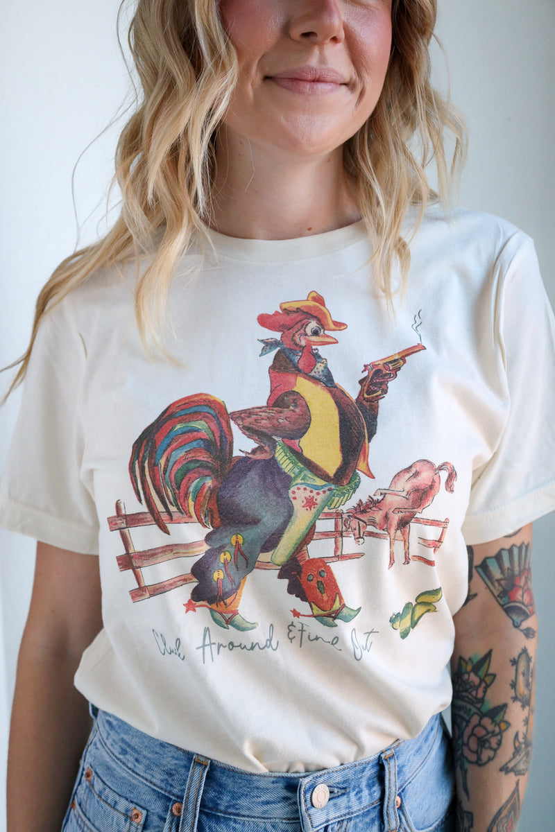 Person wearing a white t-shirt with a colorful rooster graphic design.