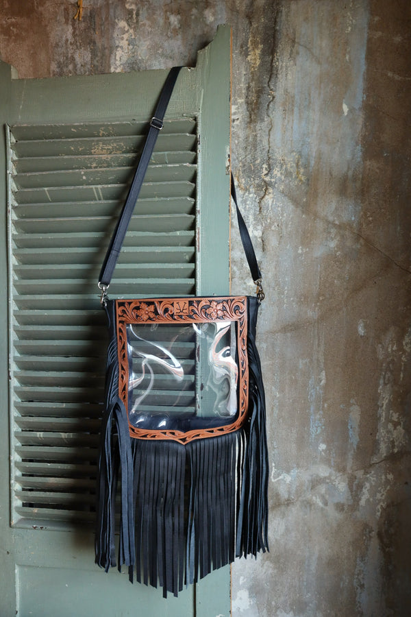 Clear stadium purse with black fringe, tan leather tooling and black strap. The purse is in the same shape as the NFR crest