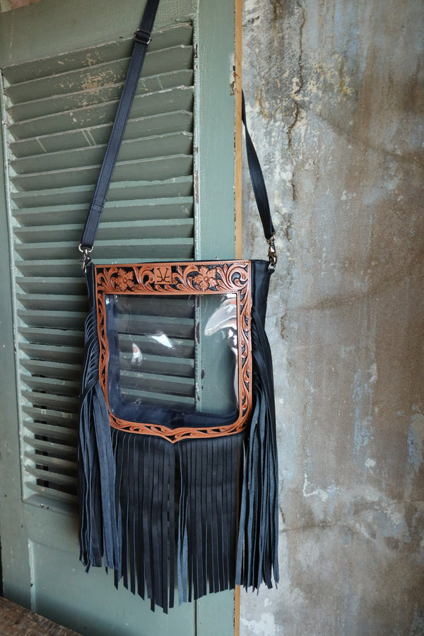 Clear stadium purse with black fringe, tan leather tooling and black strap. The purse is in the same shape as the NFR crest