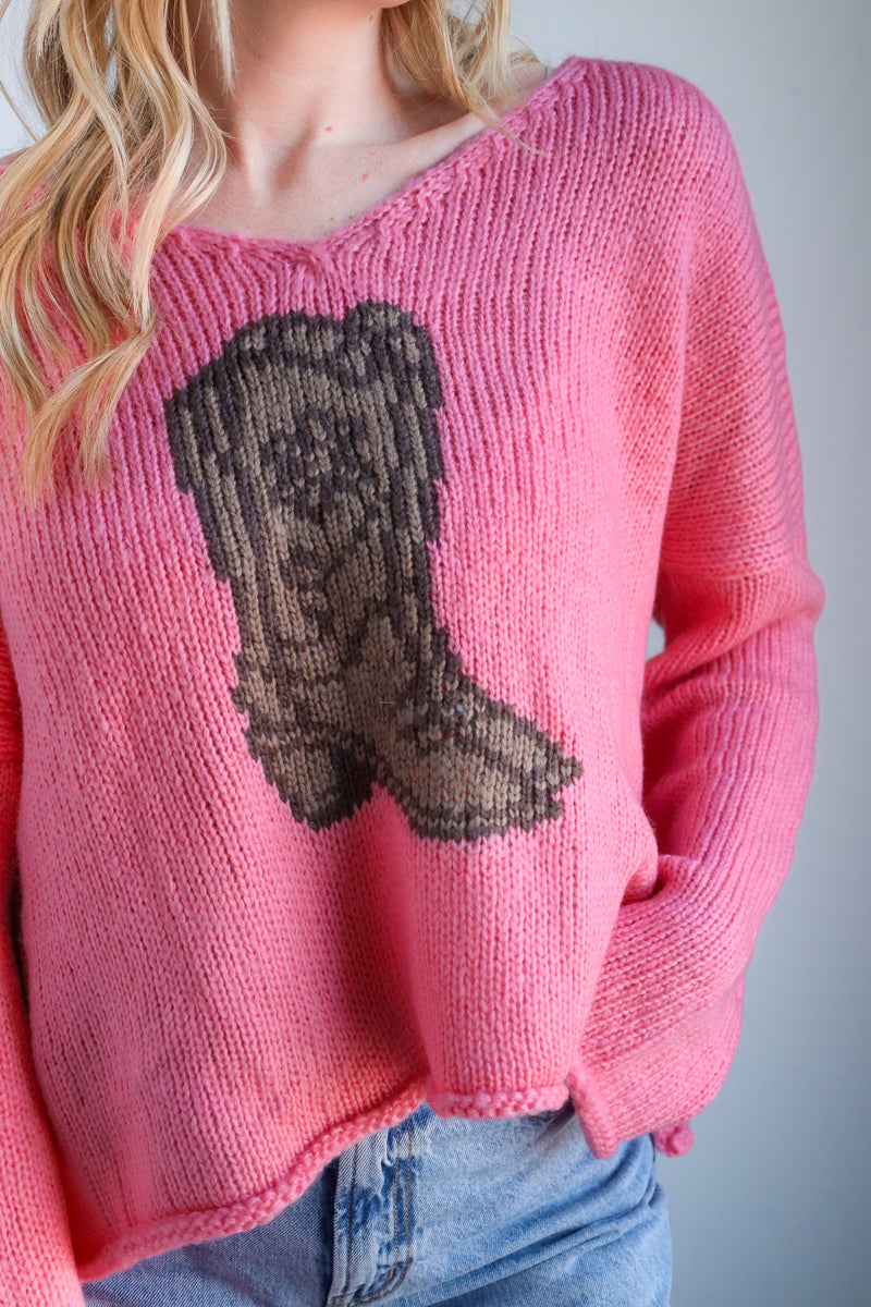 Pink sweater with a brown boot design worn by a person