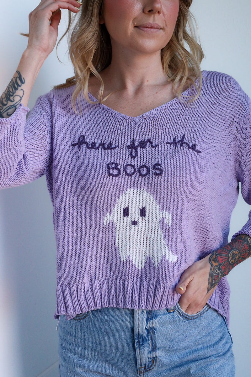 Person wearing a purple sweater with a ghost design and text.