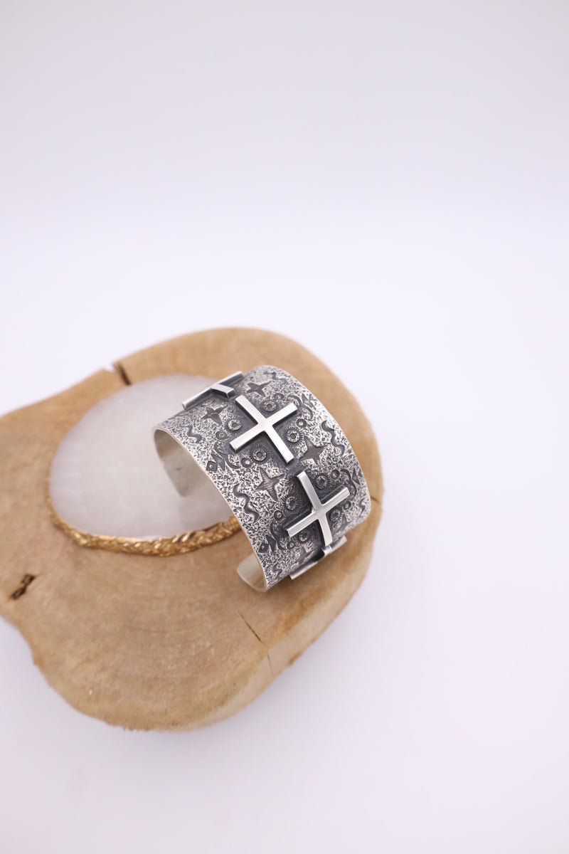 1.5 Inch width sterling silver cuff bracelet with ornate detailing and crosses in a line throughout the bracelet