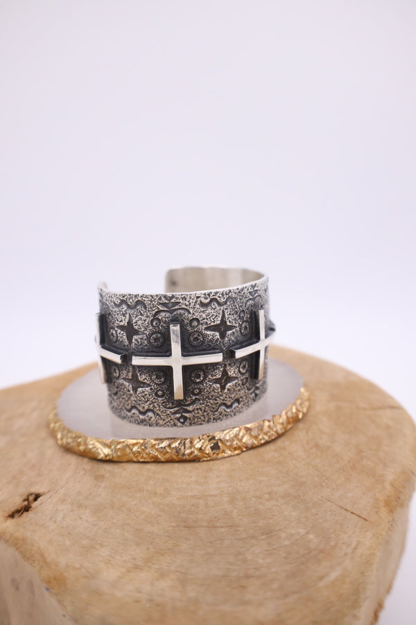 1.5 Inch width sterling silver cuff bracelet with ornate detailing and crosses in a line throughout the bracelet