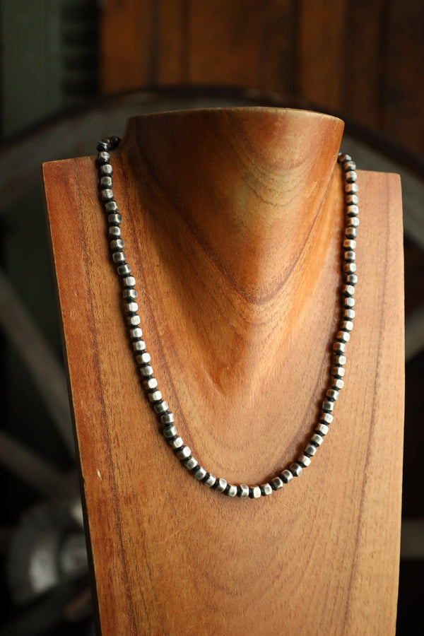 Necklace with black and silver beads on a wooden stand