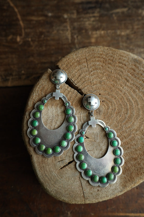Silver earrings with green beads on a wooden surface
