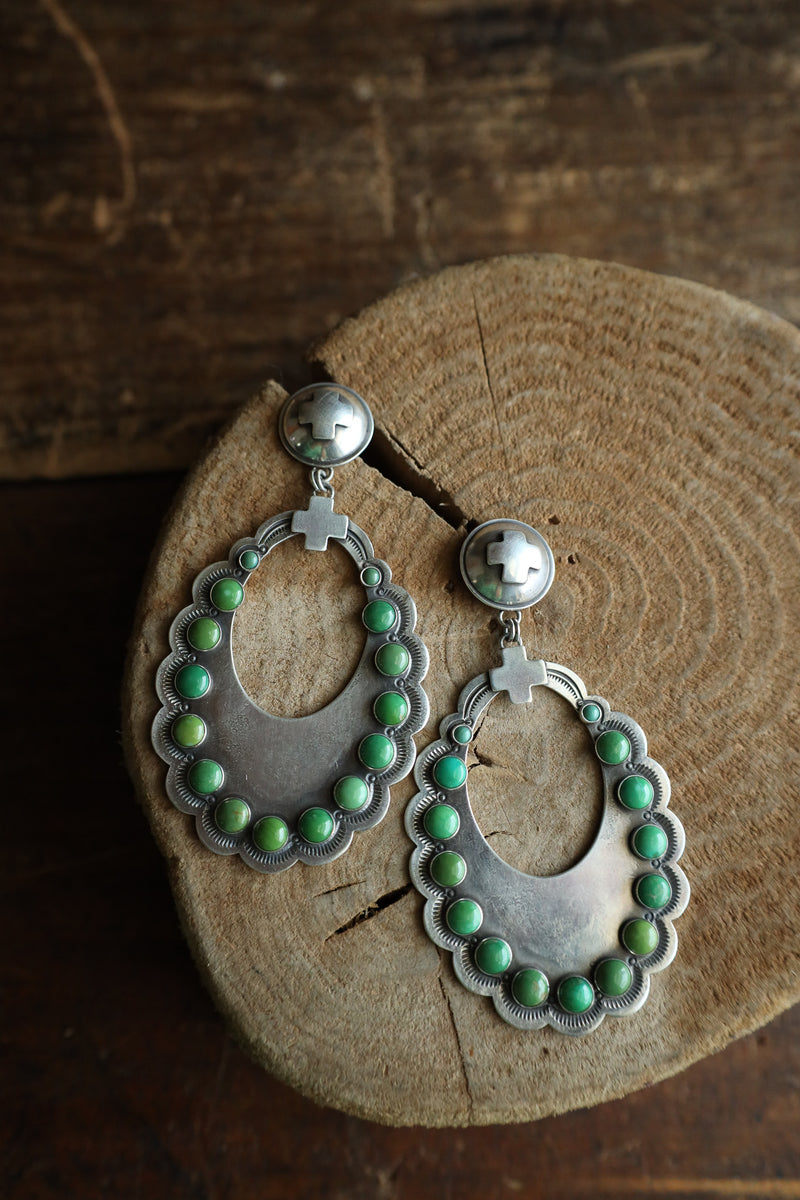 Silver earrings with green beads on a wooden surface