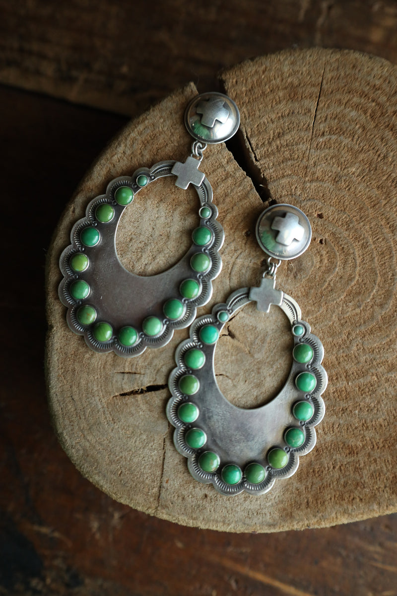 Silver earrings with green beads on a wooden surface