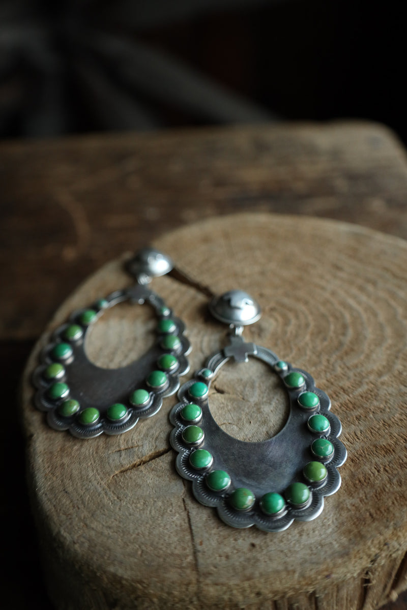 Silver earrings with green beads on a wooden surface