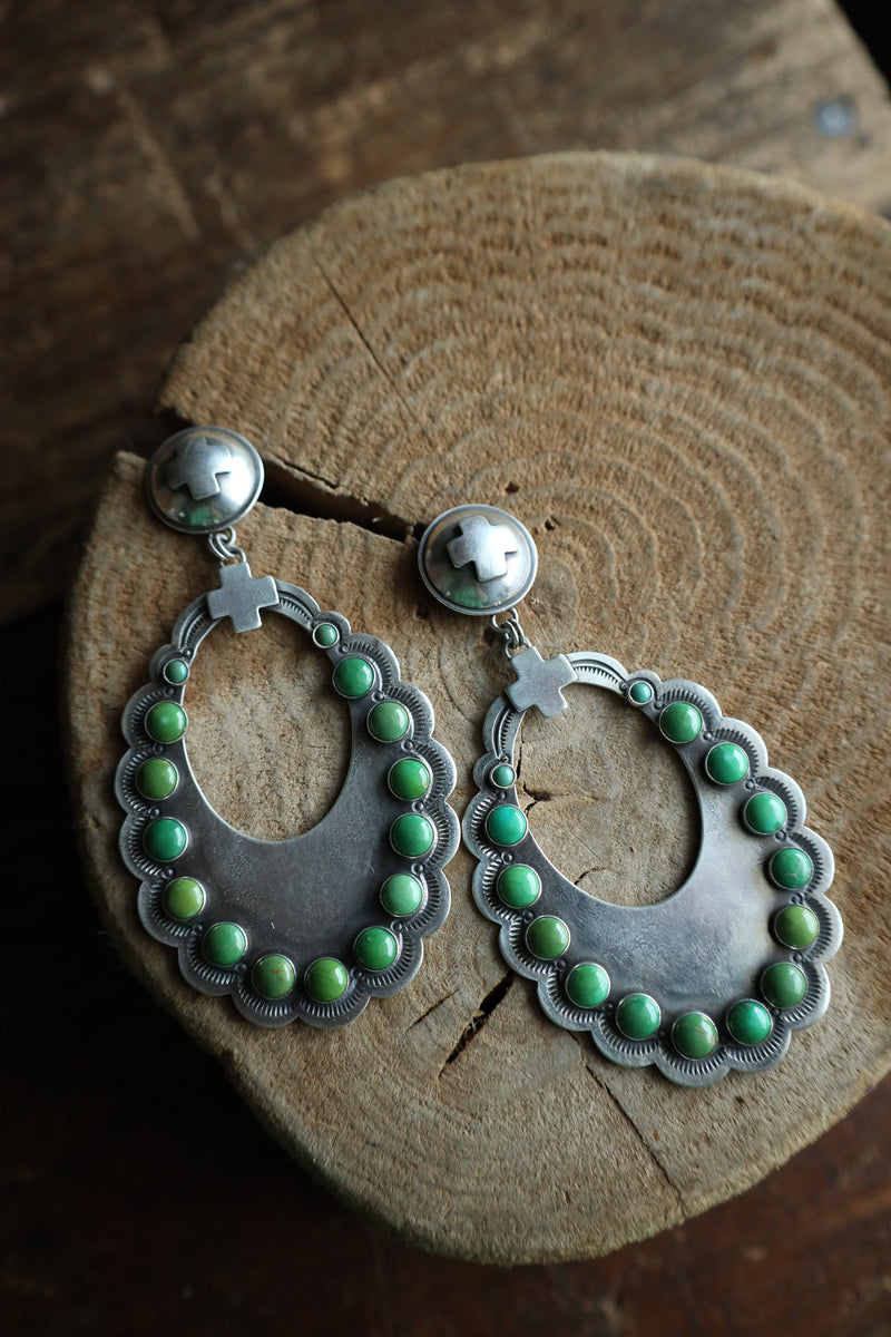 Silver earrings with green beads on a wooden surface