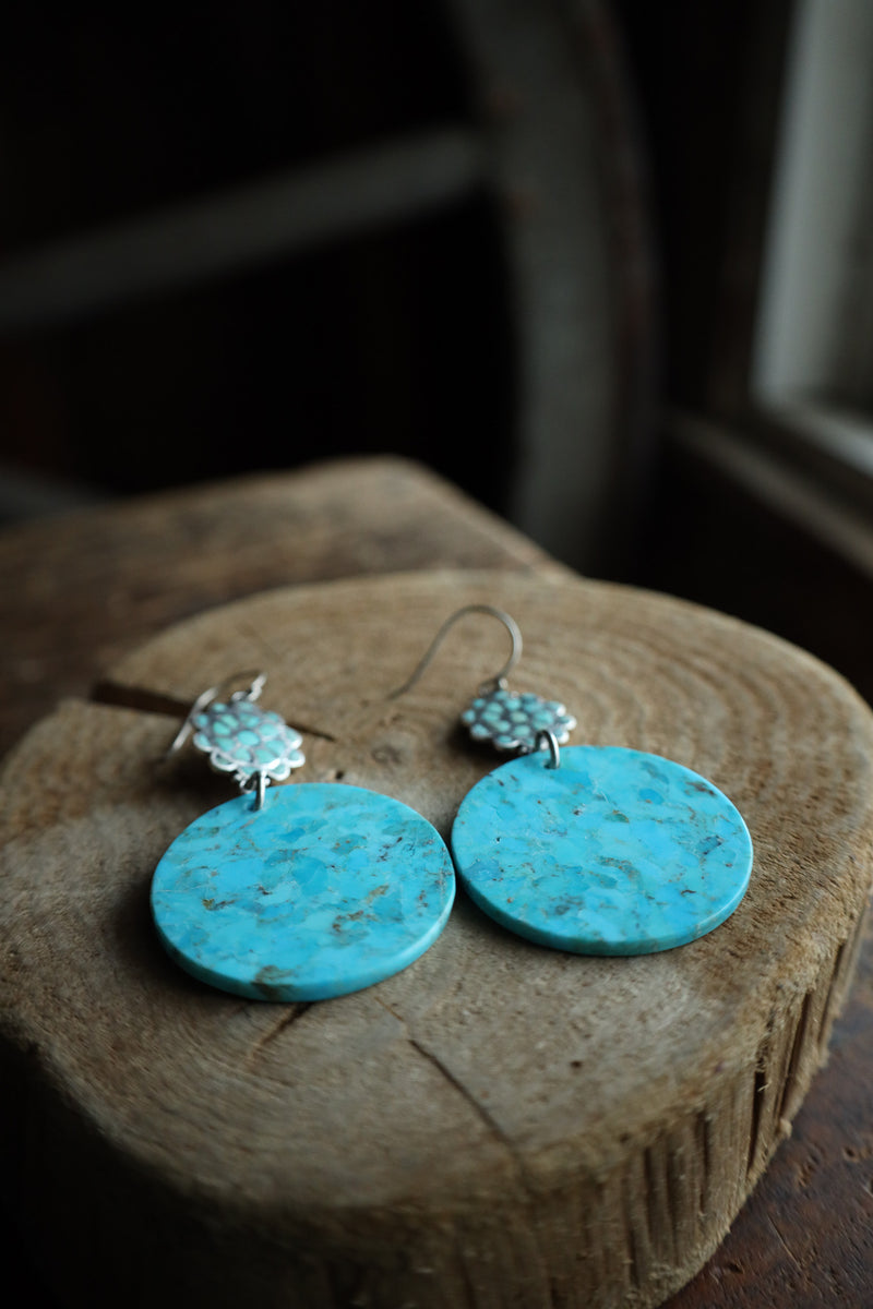 Turquoise earrings on a wooden surface with a dark background