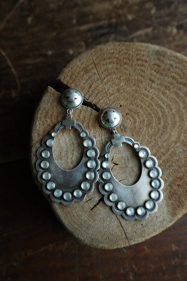 Silver hoop earrings with bead detailing on a wooden surface