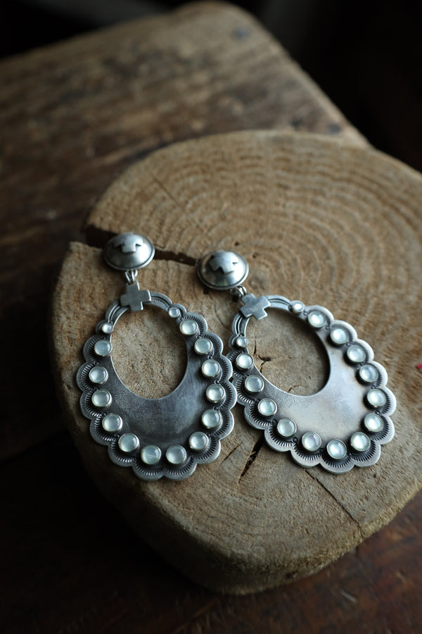 Silver hoop earrings with bead detailing on a wooden block