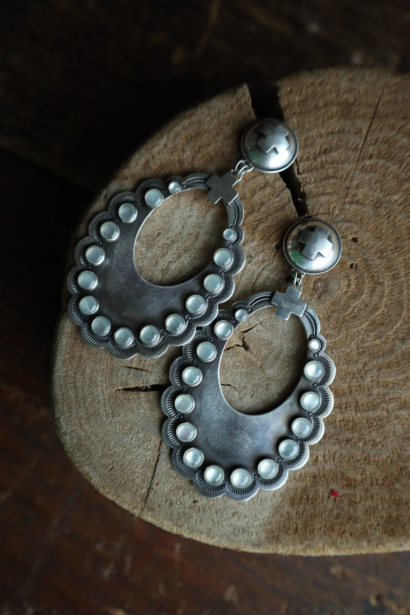 Silver earrings with bead detailing on a wooden surface
