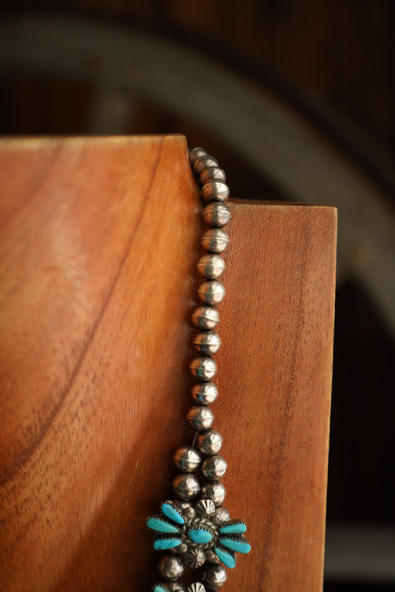 Close-up of a beaded necklace with turquoise accents on a wooden surface