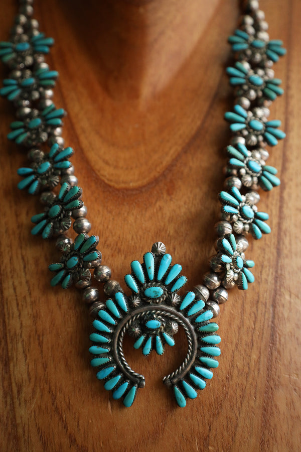 Turquoise and silver necklace on a wooden surface