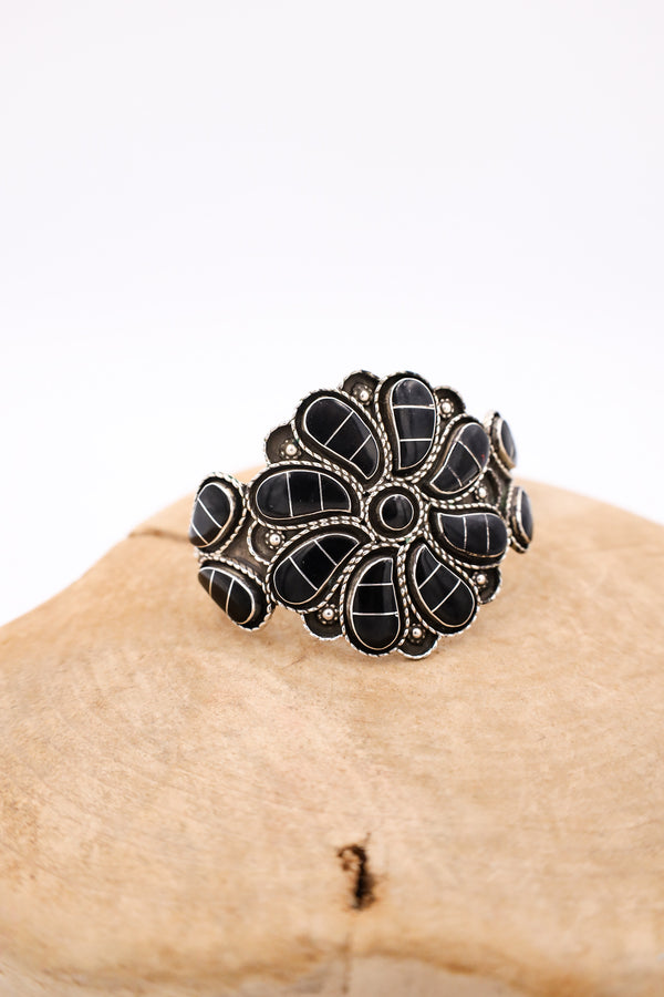 Vintage bracelet features an onyx pinwheel shape bracelet on wooden display.