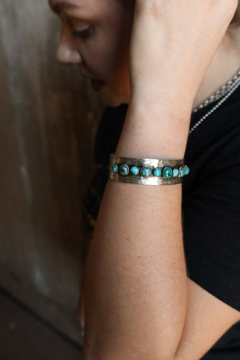 Handmade sterling silver cuff bracelet combines 5 medium and 6 small rounds of turquoise set in a beautiful line pattern