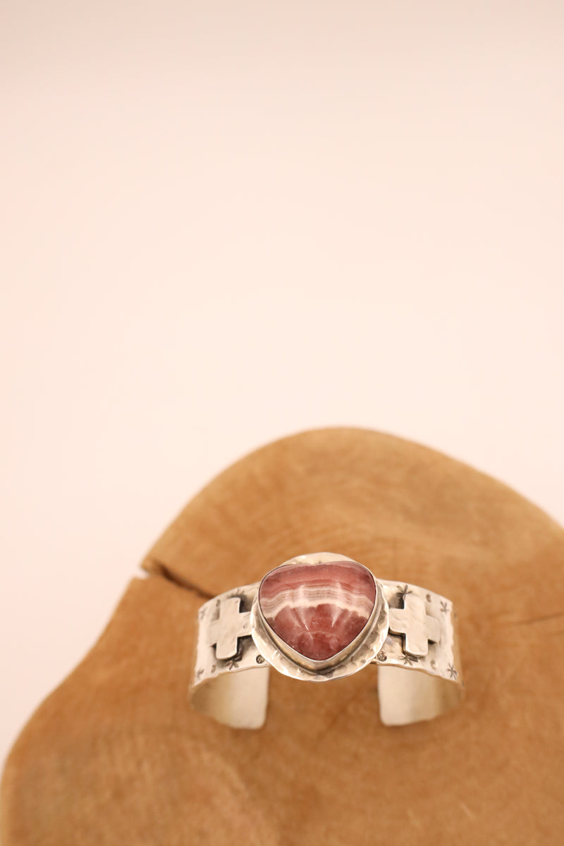 Distinctive hammered finish cuff, featuring two sterling silver crosses and a 3D rhodochrosite heart at its center