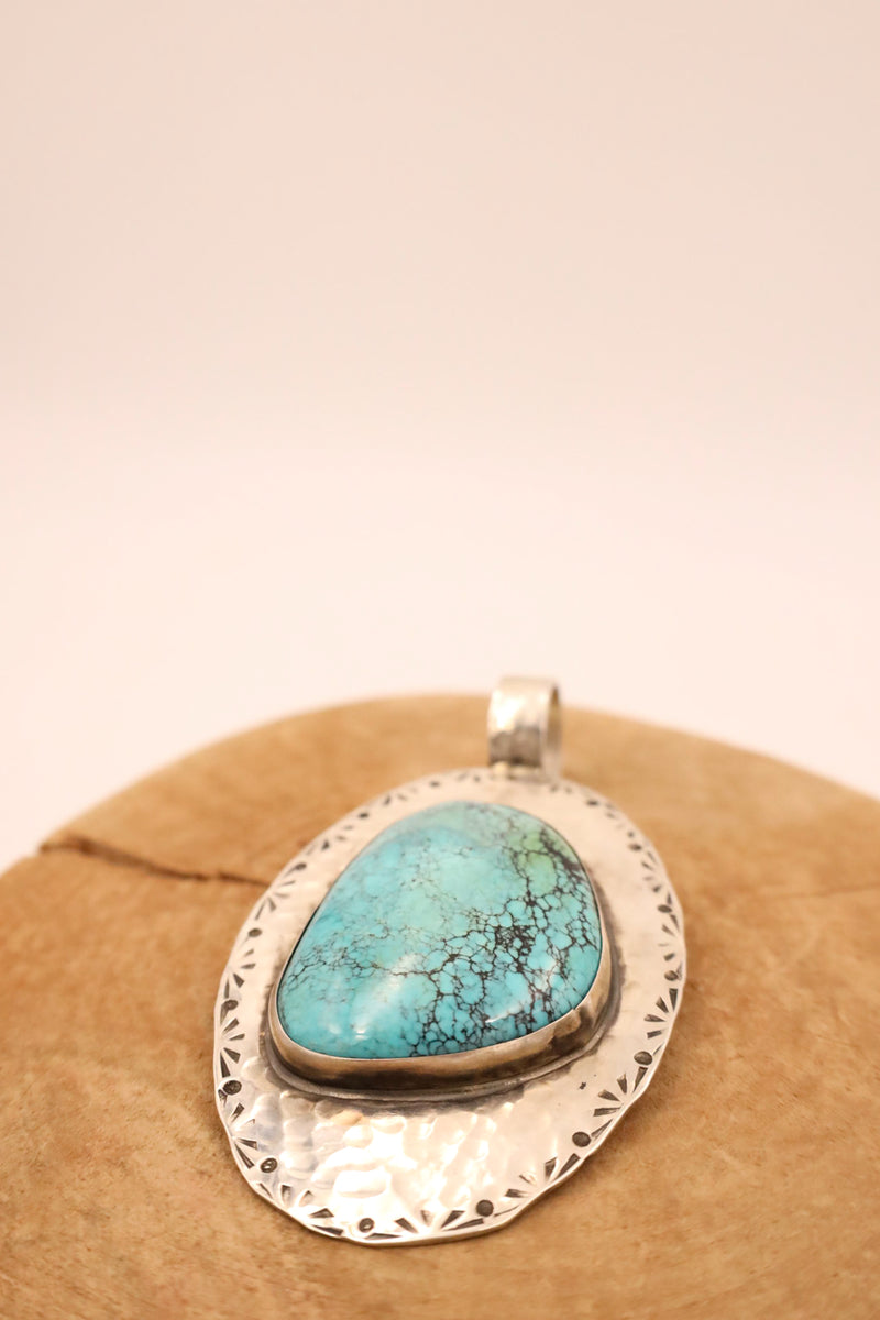 Turquoise gem pendant set in a sterling silver bezel and mounted on a hammered sterling silver oval base