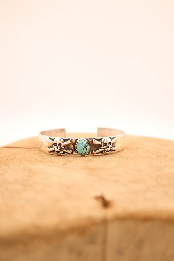 Sterling silver hammered cuff with two sterling silver skulls and crossbones with turquoise oval in the center