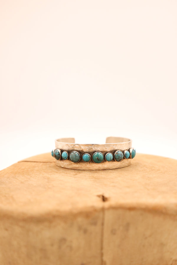 Handmade sterling silver cuff bracelet combines 5 medium and 6 small rounds of turquoise set in a beautiful line pattern