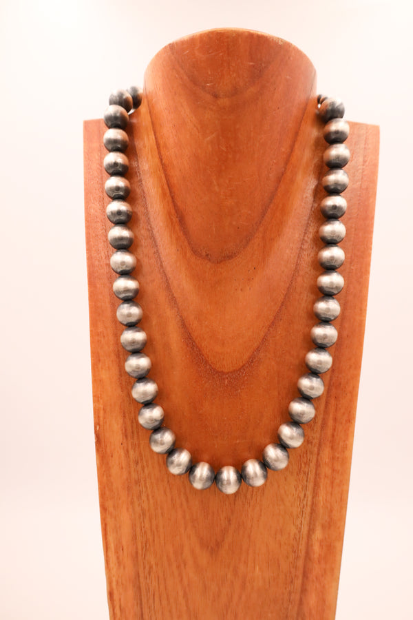Chunky Navajo pearl sterling silver beads strung on one necklace hanging on a wooden neck display