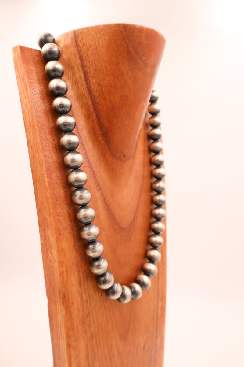 Chunky Navajo pearl sterling silver beads strung on one necklace hanging on a wooden neck display