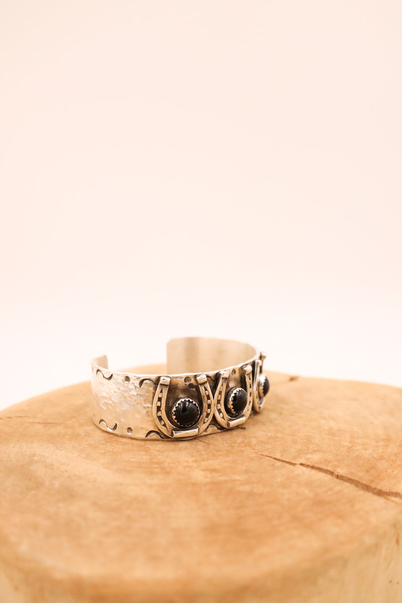 Sterling silver hammered bracelet with sterling silver horse shoes with onyx dots in the center