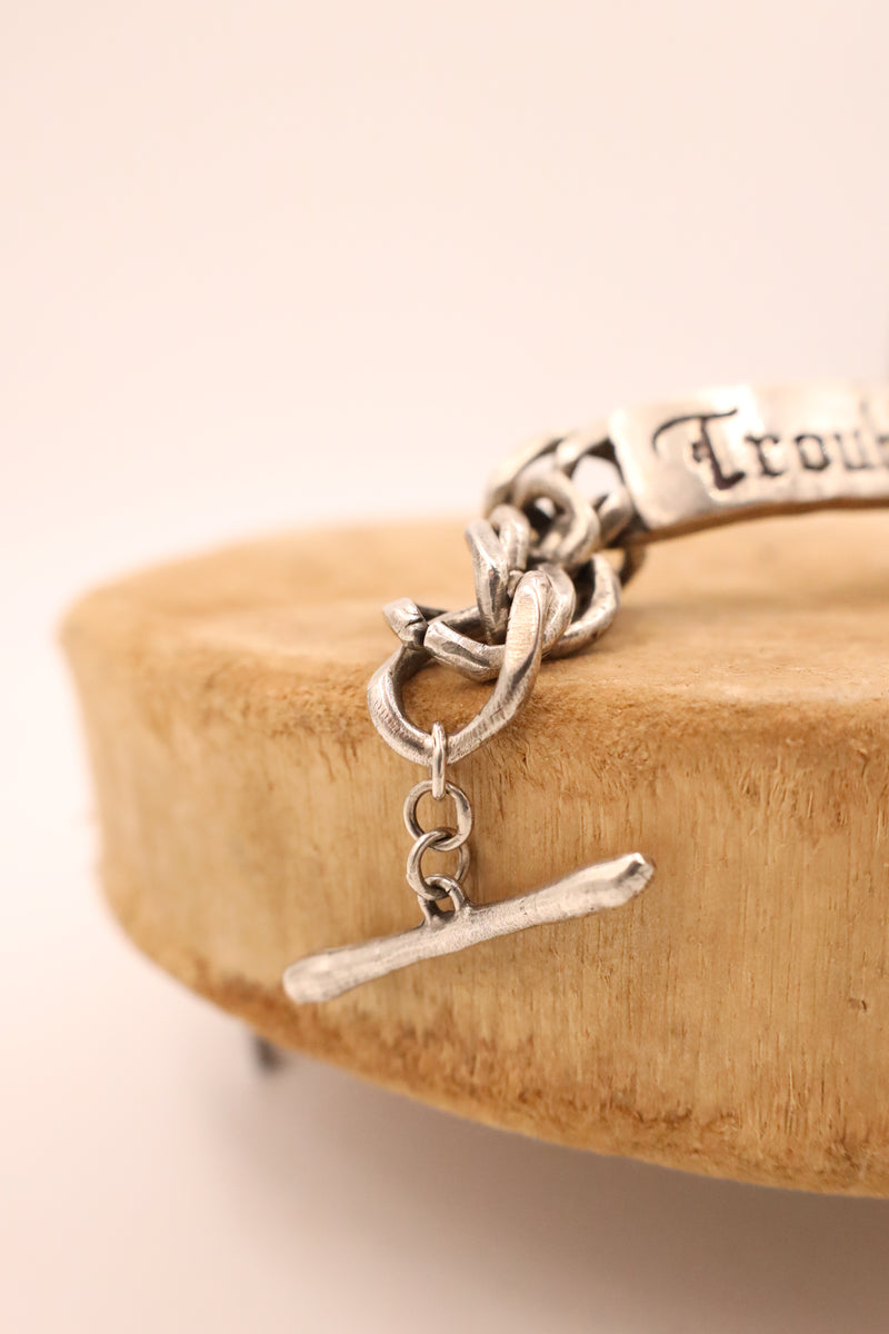 Sterling silver bracelet with script "trouble" on an ID tag