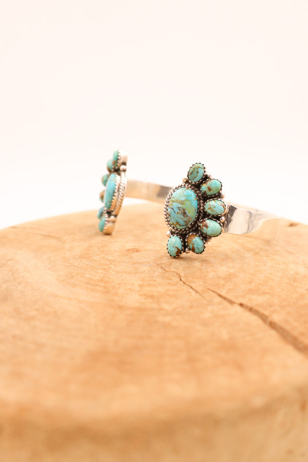 Two turquoise and brown half flowers flanking either side of a sterling silver cuff