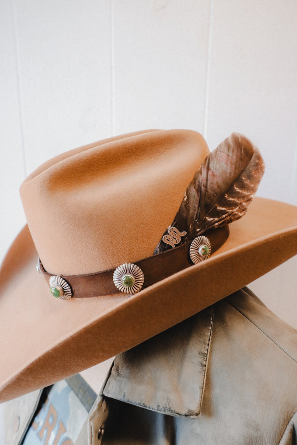 Crafted from brown leather, this hatband features 5 intricately designed pieces of turquoise surrounded by sterling silver sunbeams