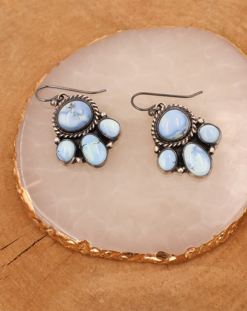 Each earring features four vibrant turquoise stones set in a sterling silver bezel