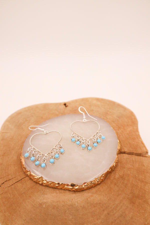Crafted from sterling silver, these heart-shaped earrings feature delicate rope details and vibrant turquoise dot dangles.