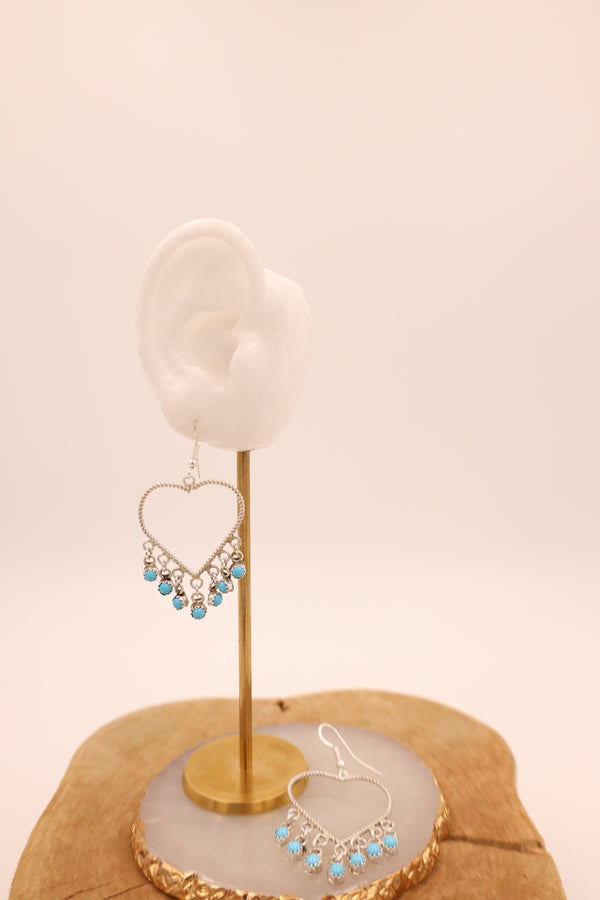 Crafted from sterling silver, these heart-shaped earrings feature delicate rope details and vibrant turquoise dot dangles.