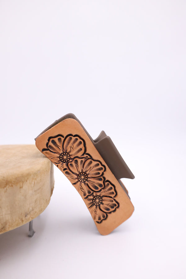 Tan claw clip with three flowers tooled into leather on each side