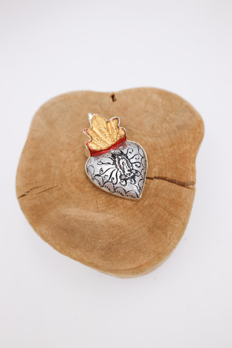 Wooden heart with golden flames and a Guadalupe milagro in the center.