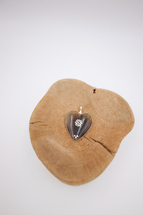 This heart is carved from horn and then stamped with a silver flower in the center.